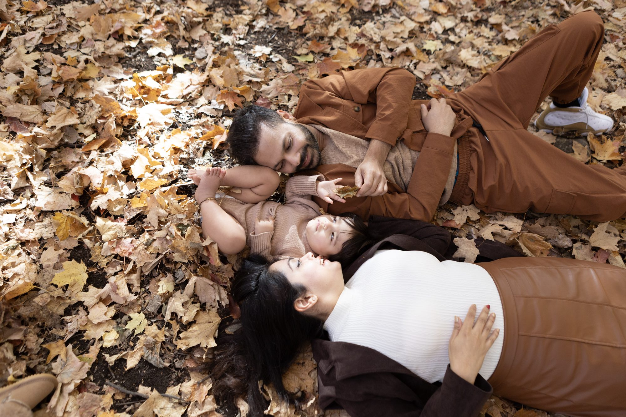 The family lying together among autumn leaves